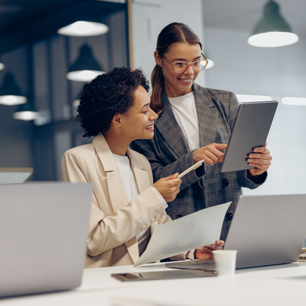 stylish-female-executives-managers-discussing-financial-accounting-papers-using-digital-tablet